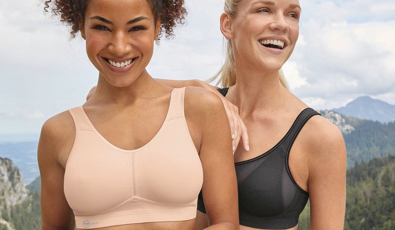 Close up of two woman wearing a beige and a black sports bra 